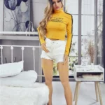 Alicine Sex Doll 163 cm IronTech Doll TPE debout, portant un haut jaune et short blanc.