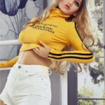 Alicine Sex Doll 163 cm IronTech Doll TPE en short blanc et pull jaune, posant debout.