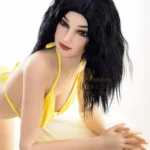 Alya Real Doll 169 cm IronTech en bikini jaune, posée à plat ventre, cheveux noirs ondulés.