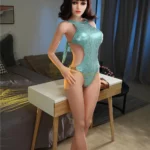 Alyza Sex Doll 165 cm en maillot vert étincelant, debout près d'un bureau moderne.
