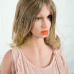 Amorea Sex Doll 160 cm IronTech Doll en robe rose, cheveux blonds, pose assise.