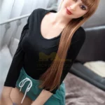 Aurélie Real Doll 165 cm IronTech, assise, cheveux longs, haut noir, short vert.