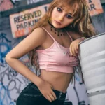 Auréline Sex Doll 163 cm IronTech en pose inclinée, top rose, short noir, fond urbain.