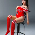 Avala Sex Doll 155 cm IronTech en tenue rouge, assise sur un tabouret, jambes croisées.