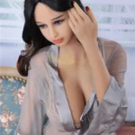 Azalée Sex Doll 163 cm IronTech, assise, peignoir transparent, cheveux noirs, regard vers la gauche.