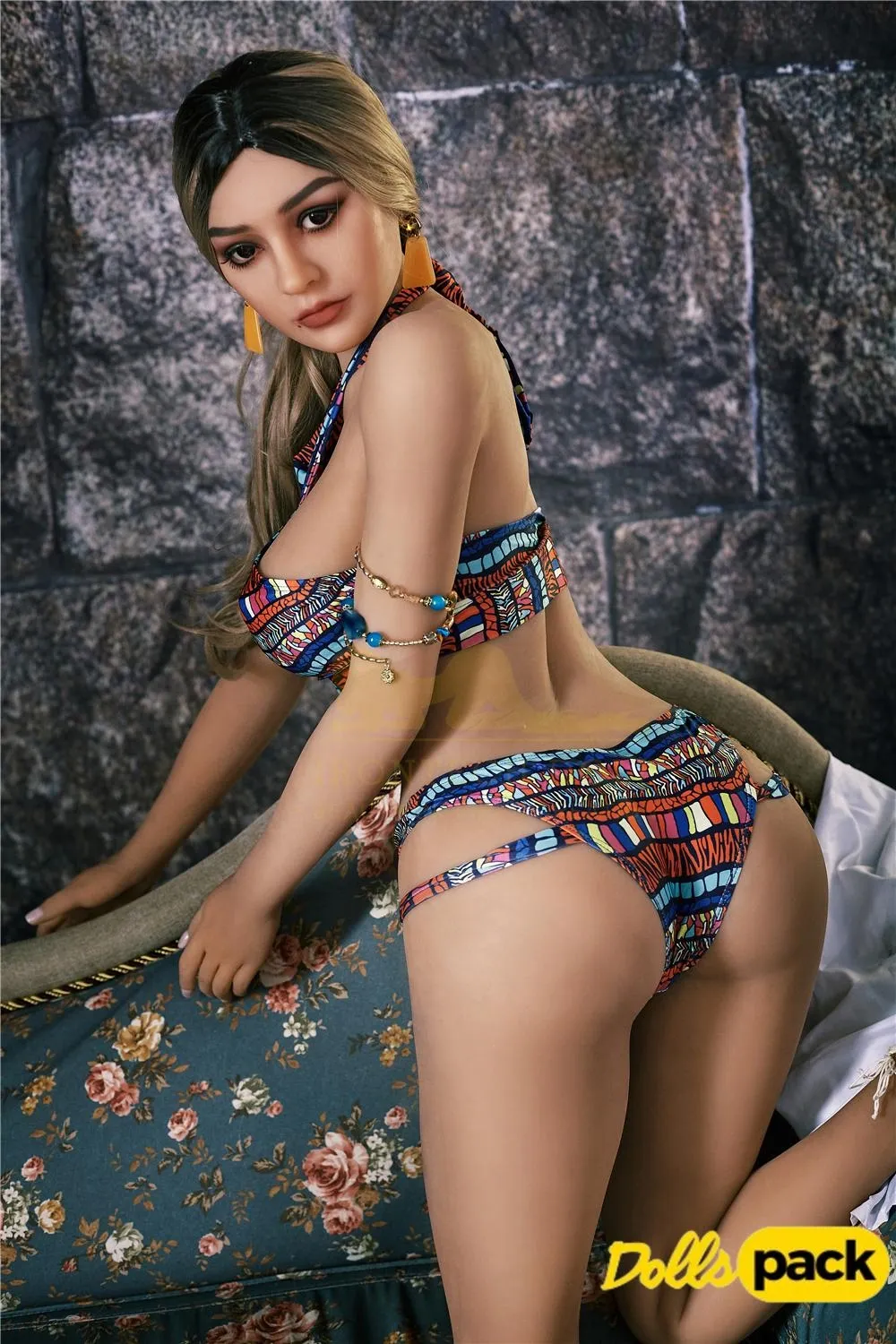 Bella Sex Doll 159 cm IronTech en bikini coloré, posée de profil sur un canapé fleuri.