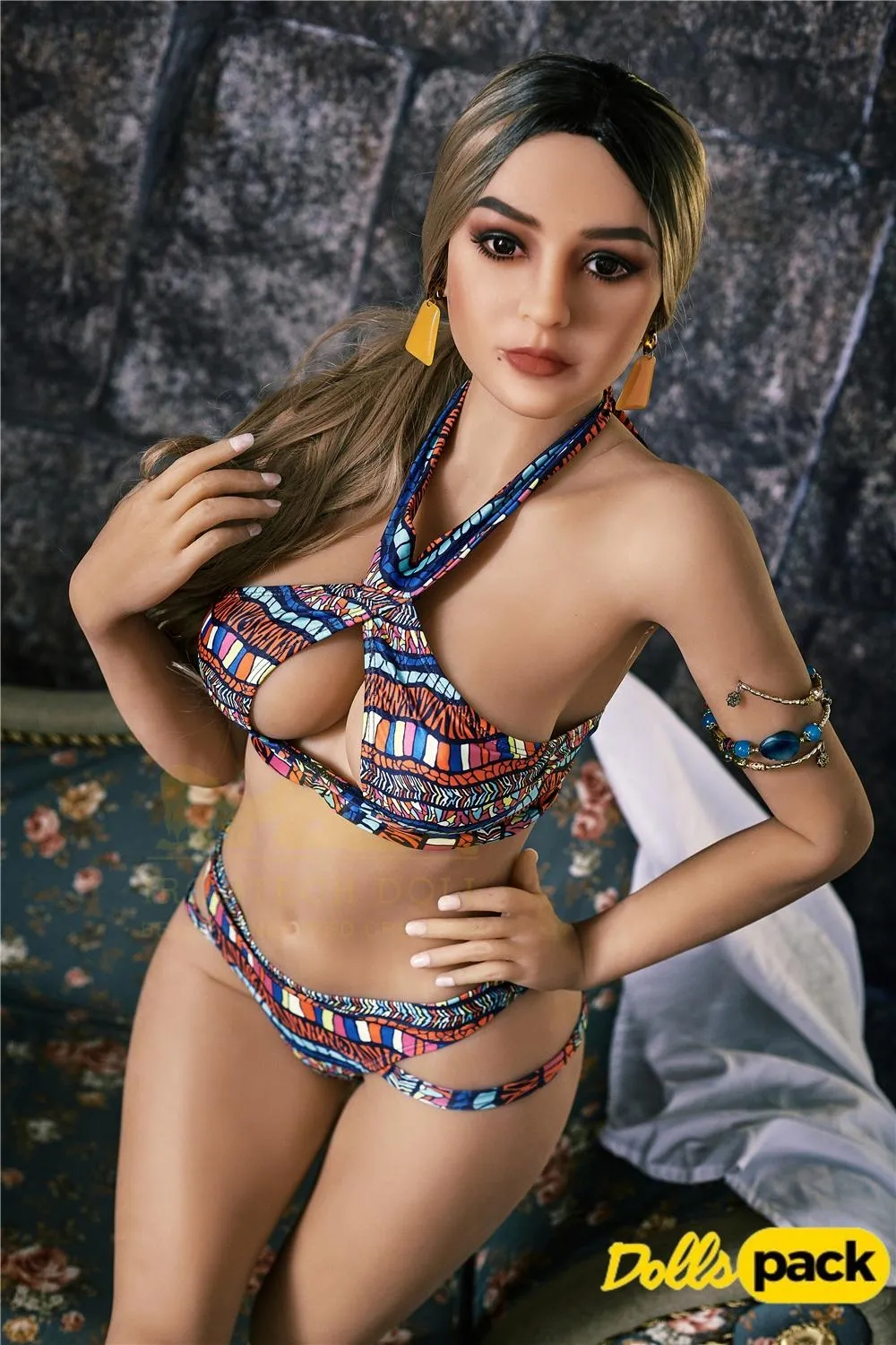 Bella Sex Doll 159 cm IronTech, pose assise, bikini coloré, fond de mur en pierre.