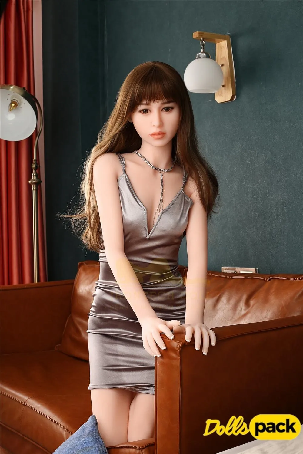 Célia Sex Doll 165 cm en robe argentée assise sur canapé marron, ambiance élégante.