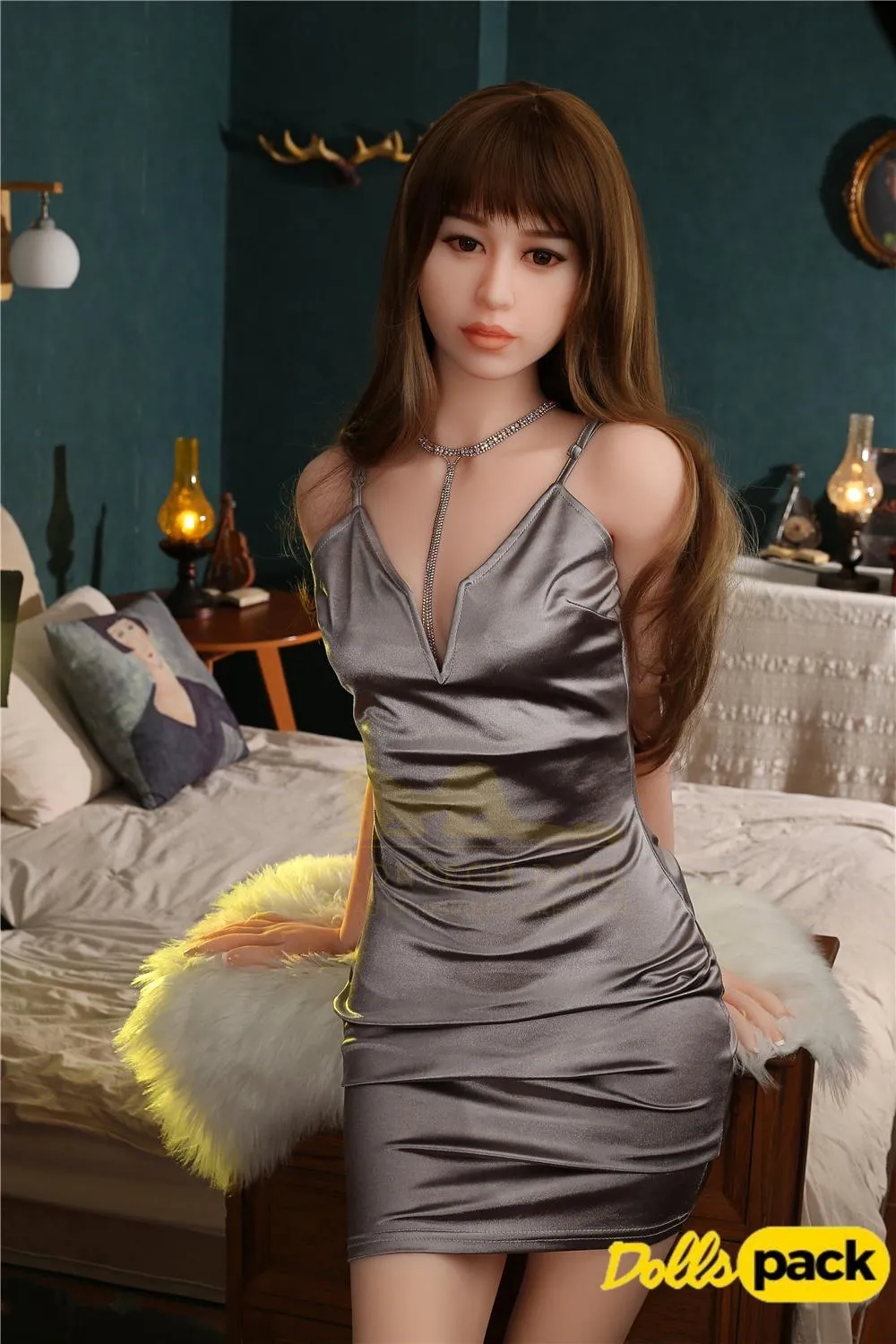 Célia Sex Doll 165 cm IronTech en robe argentée, assise sur un lit, ambiance chambre élégante.