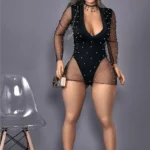 Elizara Sex Doll 156 cm IronTech en robe noire perlée, debout près d'une chaise transparente.