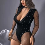 Elizara Sex Doll 156 cm IronTech en robe noire perlée, posée debout avec chaise transparente.