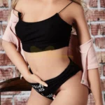Ellyana Sex Doll 155 cm IronTech en top noir, cardigan rose, fond mur en briques.