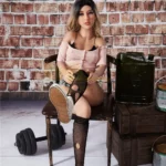 Poupée Ellyana Sex Doll 155 cm assise, tenue décontractée, fond mur de briques.