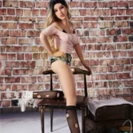 Ellyana Sex Doll 155 cm IronTech Doll TPE assise, tenue décontractée, fond mur de briques.