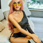 Elodora Sex Doll 165 cm IronTech Doll TPE assise sur canapé, robe noire, chapeau blanc.
