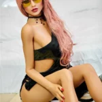 Elodora Sex Doll 165 cm IronTech Doll TPE assise, robe noire, lunettes jaunes.