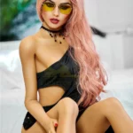 Elodora Sex Doll 165 cm IronTech en robe noire, cheveux roses, lunettes jaunes.