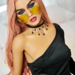Elodora Sex Doll 165 cm IronTech Doll TPE avec lunettes jaunes, robe noire, cheveux roses.