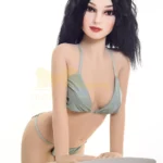 Eloïse Sex Doll 155 cm IronTech en bikini gris, posée debout, appuyée sur une table blanche.