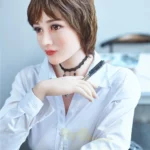 Elsalune Sex Doll 159 cm IronTech, pose assise, chemise blanche, cheveux courts bruns.