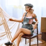 Emmelya Sex Doll 163 cm en salopette, assise, peignant sur chevalet, ambiance artistique.