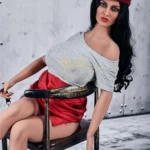 Enora Sex Doll 163 cm assise, tenue décontractée, béret rouge, ambiance moderne.