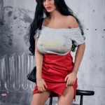 Enora Sex Doll 163 cm IronTech, pose assise, jupe rouge, béret rouge, fond industriel.