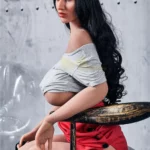 Enora Sex Doll 163 cm assise, portant un béret rouge et un haut gris décontracté.