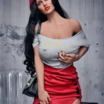 Enora Sex Doll 163 cm en jupe rouge et béret, posant avec élégance devant une chaise transparente.