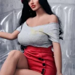 Enora Sex Doll 163 cm assise, portant un béret rouge et une jupe, sur un fauteuil transparent.