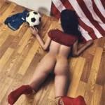 Evalia Sex Doll 163 cm IronTech allongée sur le ventre, drapeau USA, ballon de foot.
