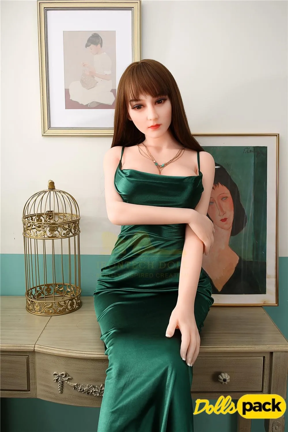 Glamazelle Sex Doll 165 cm en robe verte, assise élégamment sur une commode.