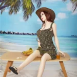 Isabelle Sex Doll 157cm IronTech en robe fleurie, assise sur une table de plage, chapeau de paille.
