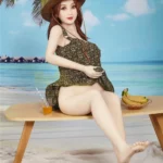 Isabelle Sex Doll 157cm IronTech en robe d'été, assise sur un banc de plage avec chapeau.