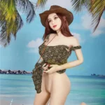 Isabelle Sex Doll 157cm IronTech Doll TPE en bikini fleuri, posant à genoux sous un palmier.