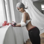 Isadora Sex Doll 158 cm IronTech en tenue de sport, appuyée contre une fenêtre.
