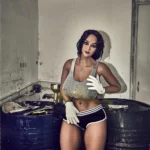 Léoline Sex Doll 158 cm IronTech en tenue sportive, pose debout près de barils.