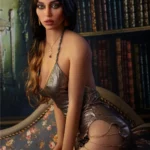 Lidora Sex Doll 163 cm IronTech Doll TPE en robe métallisée, posée de profil sur canapé.