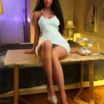 Lilinka Sex Doll 164 cm assise sur une table, robe blanche, ambiance chaleureuse.