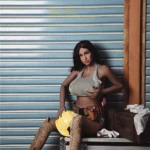 Lilizelle Sex Doll 163 cm IronTech en tenue de travail, posée contre un mur avec casque et outils.