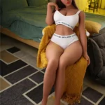 Lilouanne Sex Doll 164 cm assise sur un fauteuil jaune, en lingerie blanche, ambiance chambre.