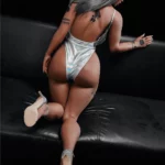 Liluri Sex Doll 158 cm IronTech Doll TPE en body argenté, posée à genoux sur un canapé noir.