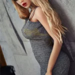 Lilydoll Sex Doll 169 cm IronTech en robe grise, pose latérale élégante contre un mur.