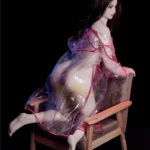 Lolika Sex Doll 168 cm en robe transparente, posée sur un fauteuil, vue de profil.