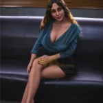 Lorabelle Sex Doll 161 cm IronTech en robe bleue assise sur canapé noir, jambes croisées.