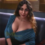 Lorabelle Sex Doll 161 cm IronTech, assise sur un canapé, robe bleue, cheveux ondulés.