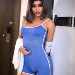 Lovena Luv Sex Doll 168 cm en combinaison bleue, debout contre un mur.