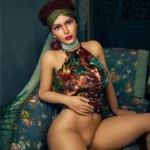 Lulika Sex Doll 164 cm IronTech TPE assise sur canapé, tenue colorée, ambiance exotique.