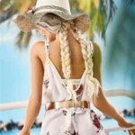 Lullia Valentina Sex Doll en robe fleurie, chapeau de paille, vue de dos, plage en arrière-plan.