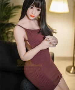 Luluca Sex Doll 161 cm IronTech en robe bordeaux, assise sur canapé, éclairage doux.